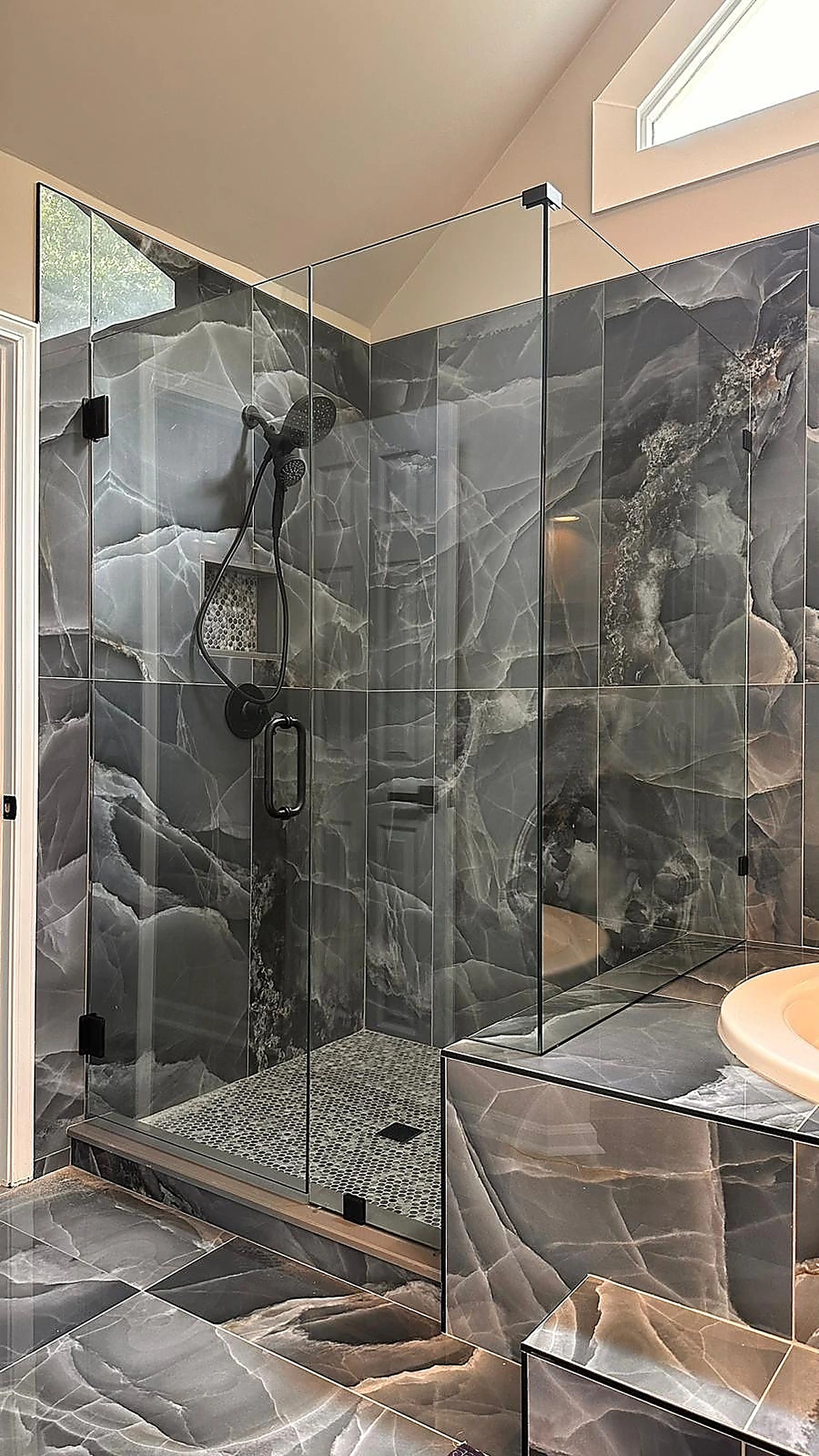Glass shower with dark veined marble tile in a South Florida remodel