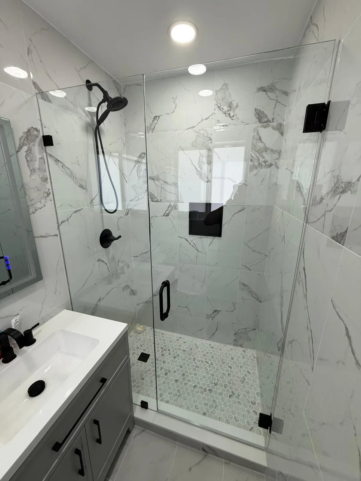 Frameless glass shower with marble tile walls