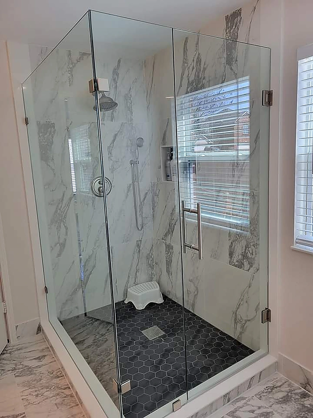 Corner glass shower with marble tile and rain shower head