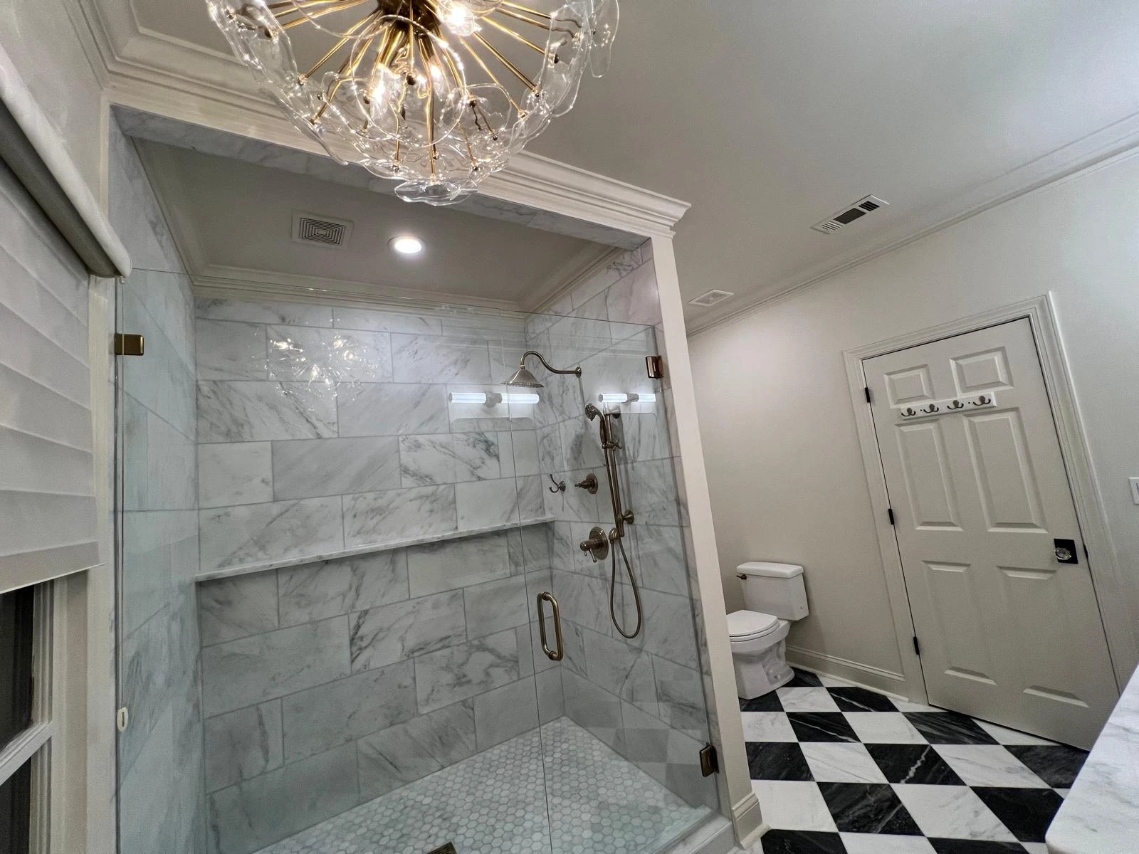 Marble shower enclosure lit by a crystal chandelier in a South Florida master bathroom — Deerfield Beach, FL