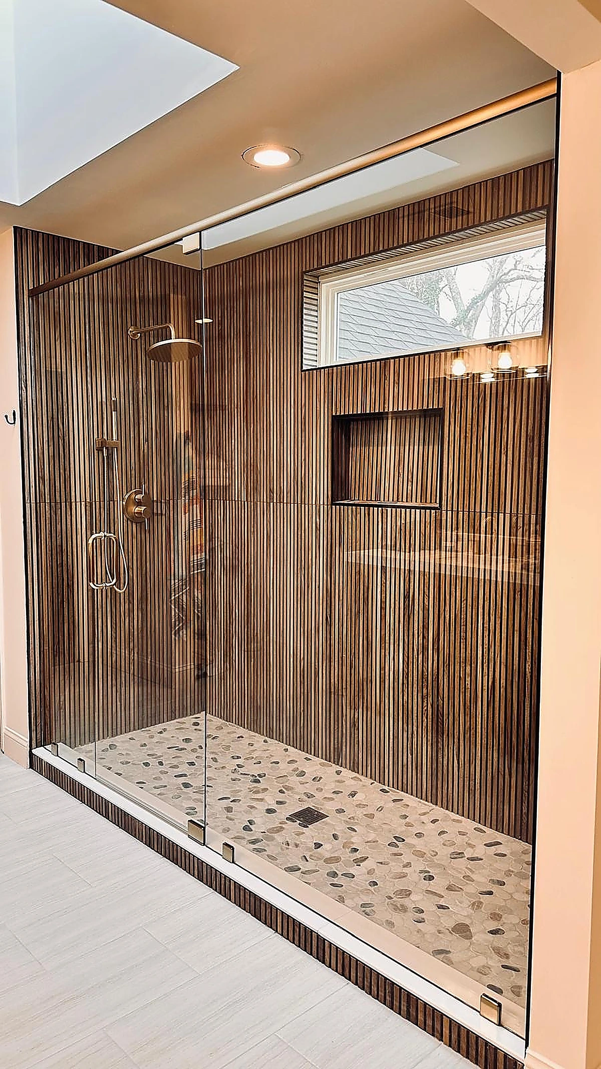 Ribbed wood-look tile shower with brass rain shower fixtures