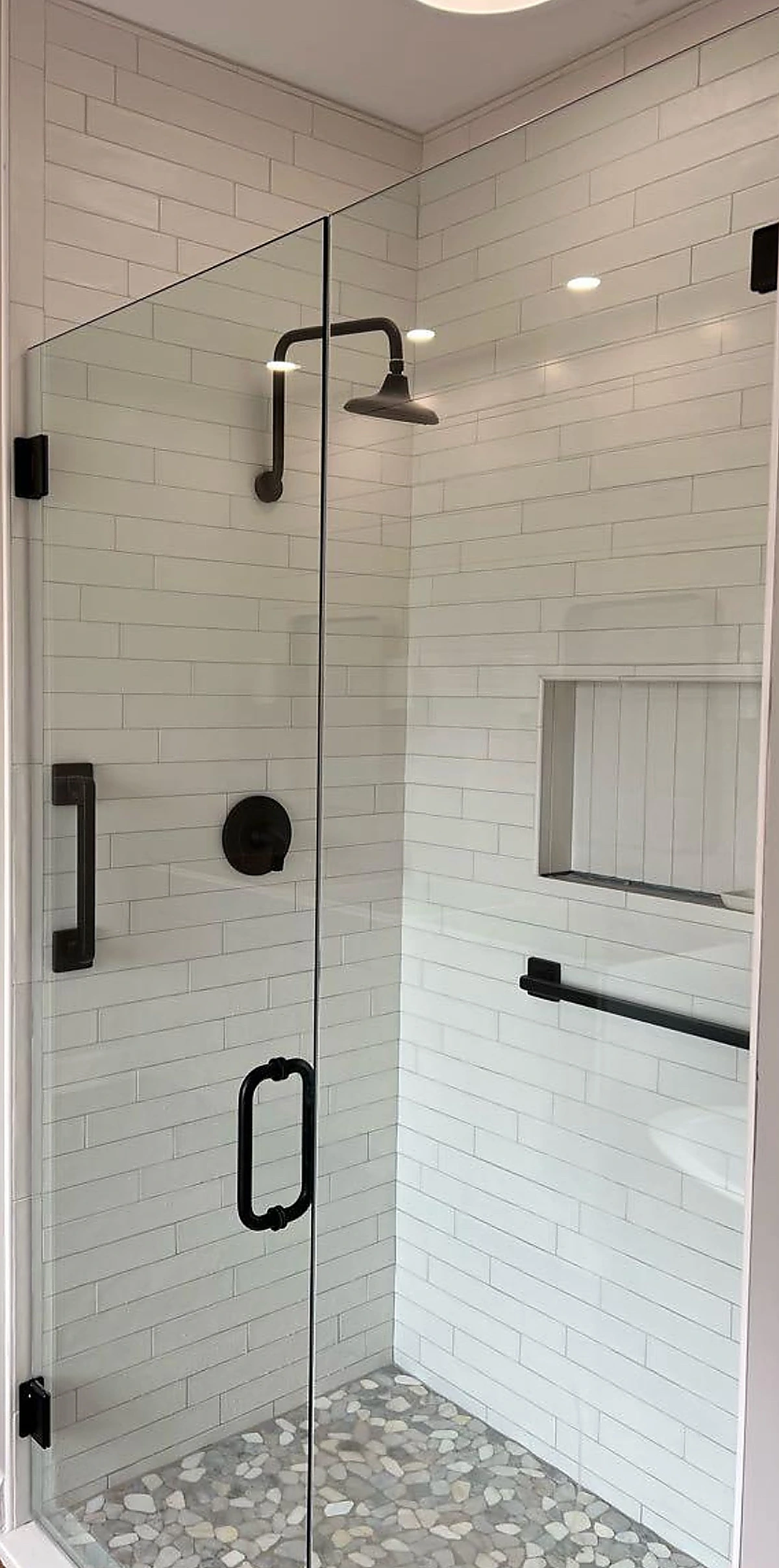Glass shower with white subway tile and black fixtures