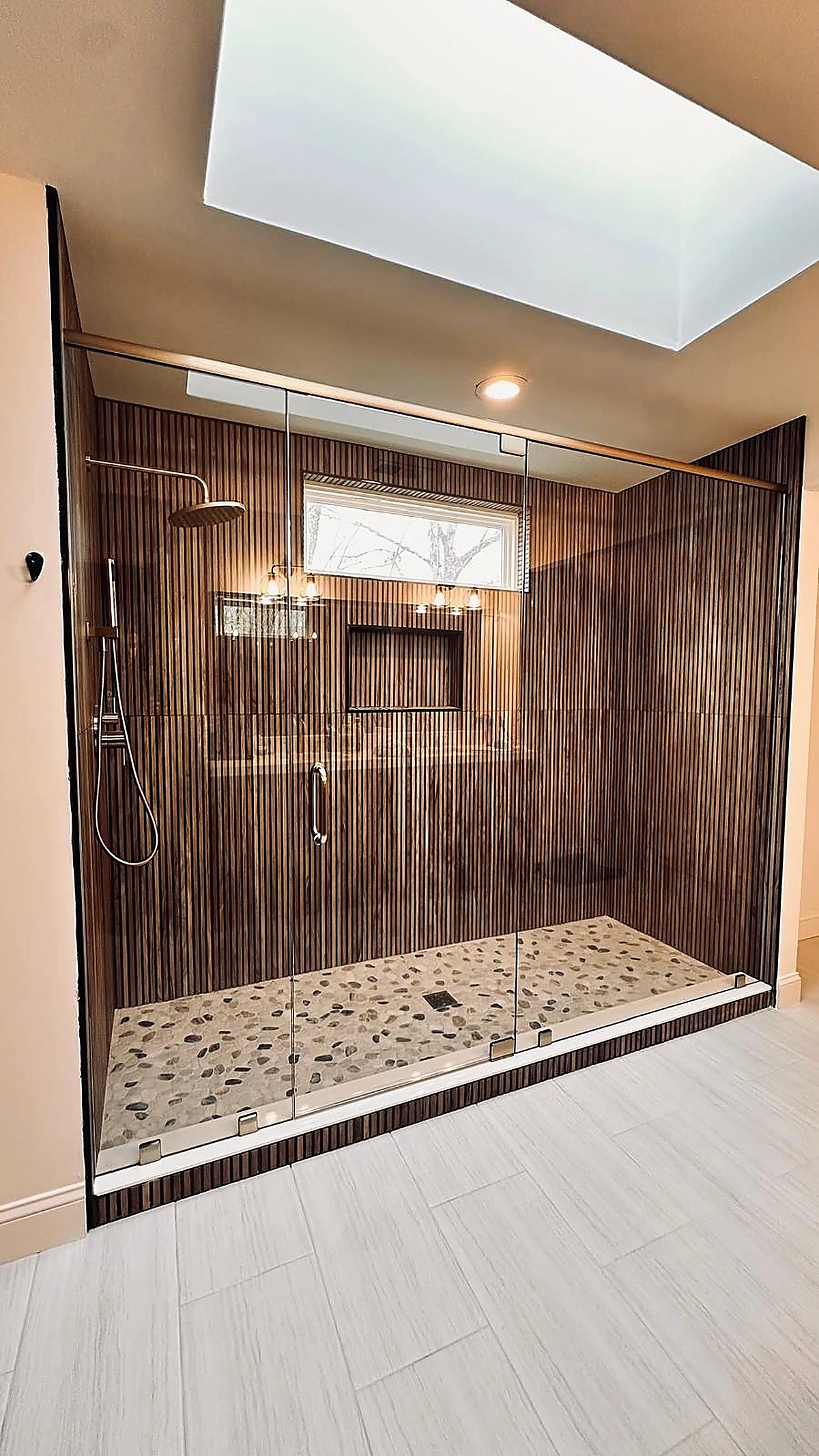 Wood-look ribbed tile shower with skylight and pebble stone shower pan