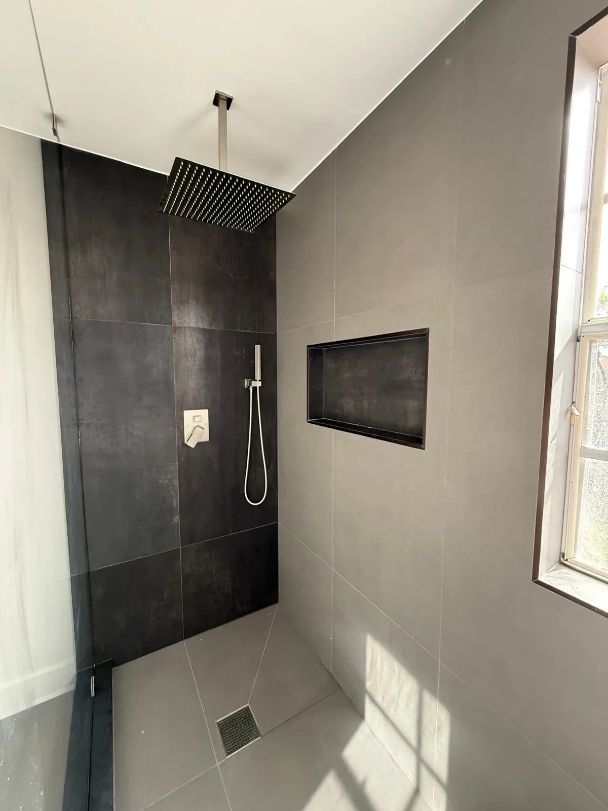 Charcoal tile shower with rainfall head and frameless glass