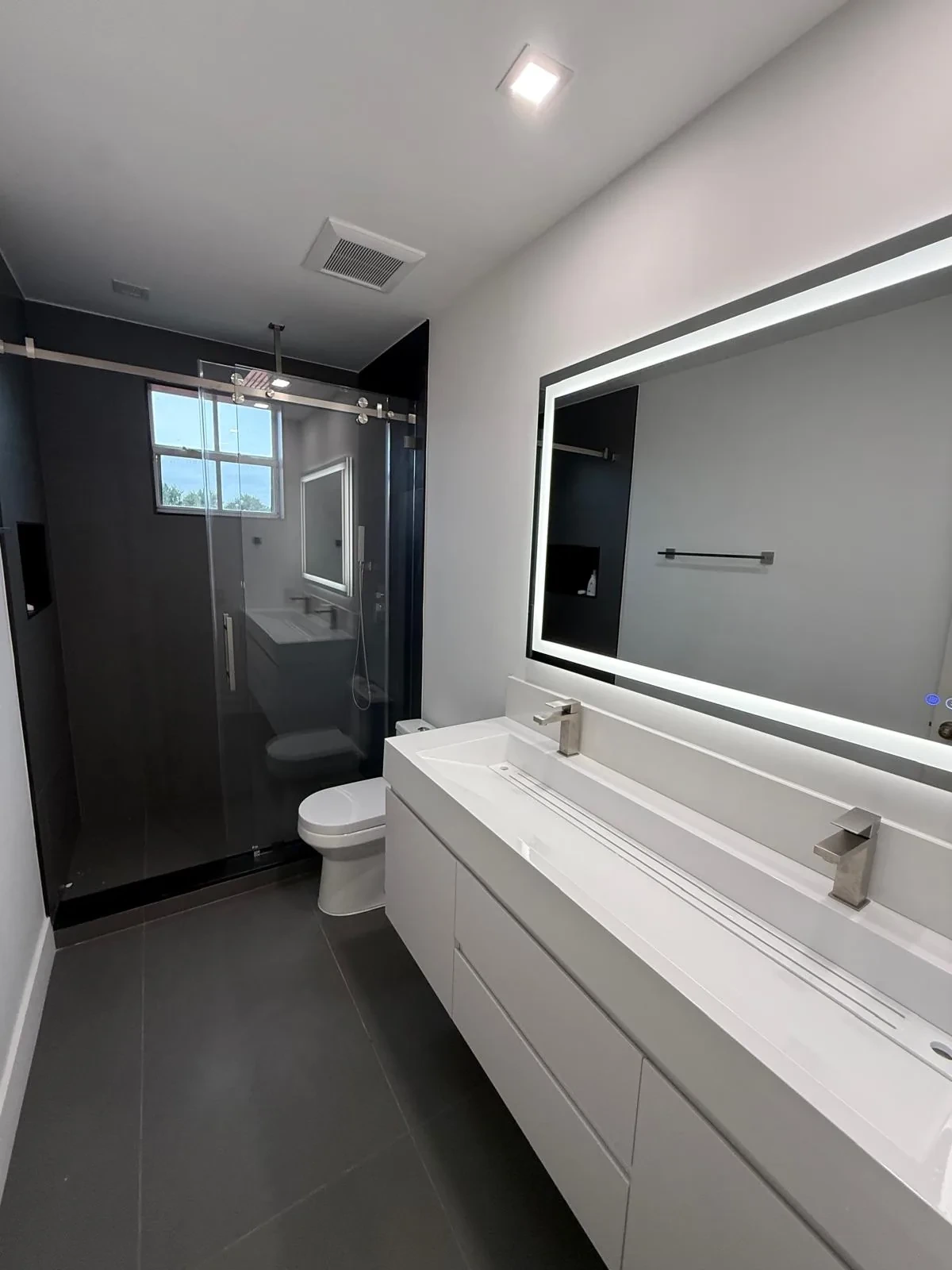 Bathroom with sliding glass shower door and backlit LED mirror