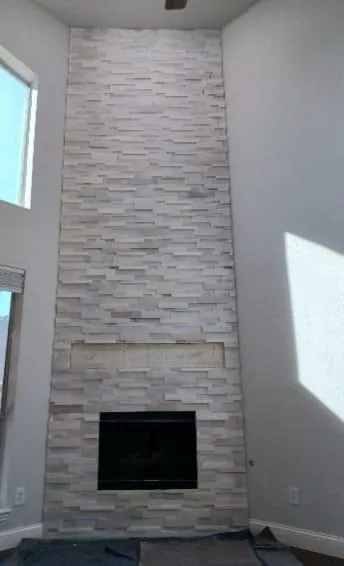 Custom stone veneer fireplace and decorative accent wall installation in luxury South Florida living room