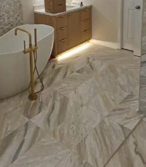 Luxury bathroom marble tile floor installation with freestanding soaking tub and gold fixtures in South Florida residence