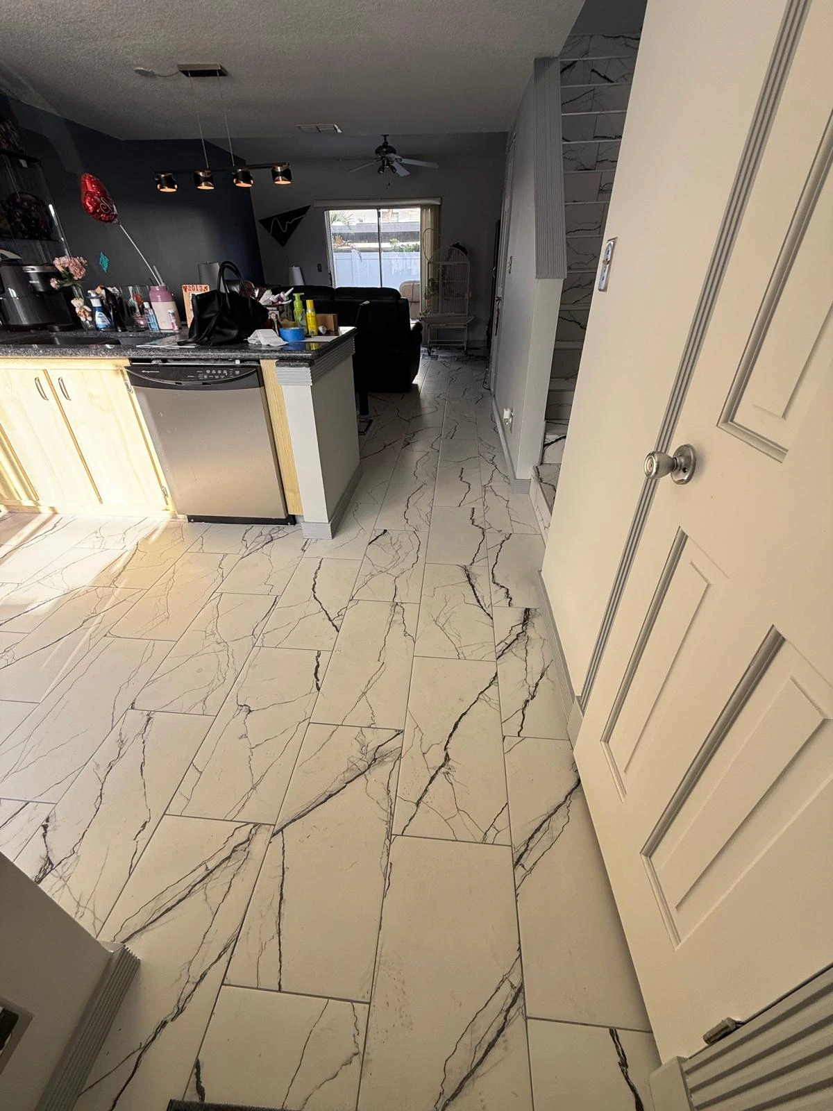 Marble-look porcelain tile floor spanning kitchen and living area in South Florida home by Primer Star Corp